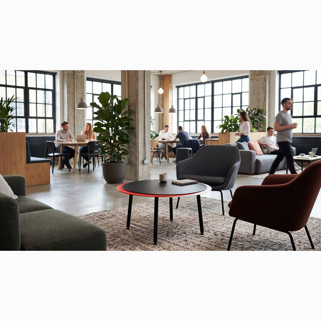 A black, red and white Stacked coffee table takes centre stage between a sofa and 2 lounge chairs in a bustling, open plan communal space.