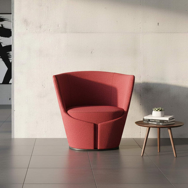 A Dapper Armchair in red fabric in front of a concrete wall in a modern loft space.