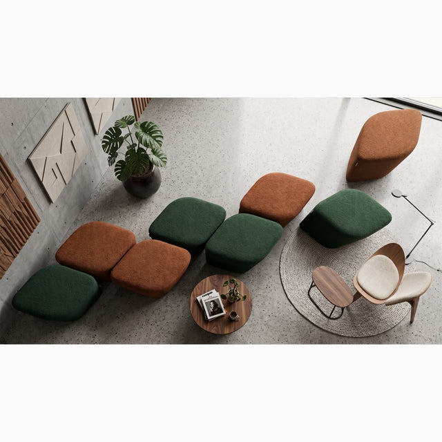 A modern lounge area in a public space with multiple upholstered ottomans in green and rust orange, neatly arranged in a line to keep things tidy and uncluttered when not in use.