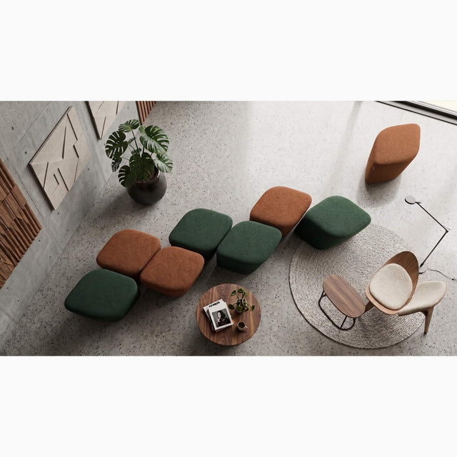 A modern lounge area in a public space with multiple upholstered ottomans in green and rust orange, neatly arranged in a line to keep things tidy and uncluttered when not in use.
