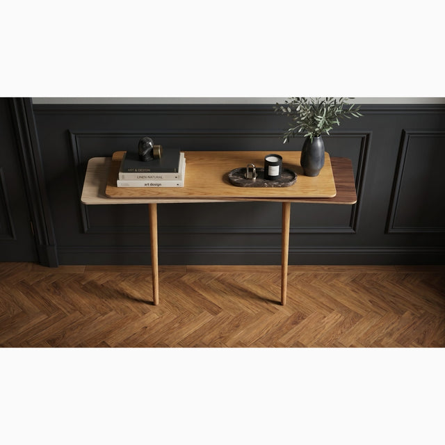 A beautifully decorated hallway with dark wall panels and a herringbone wood floor features a Stacked console table. The console has an Oak top, Walnut middles and Ash bottom with oak legs.