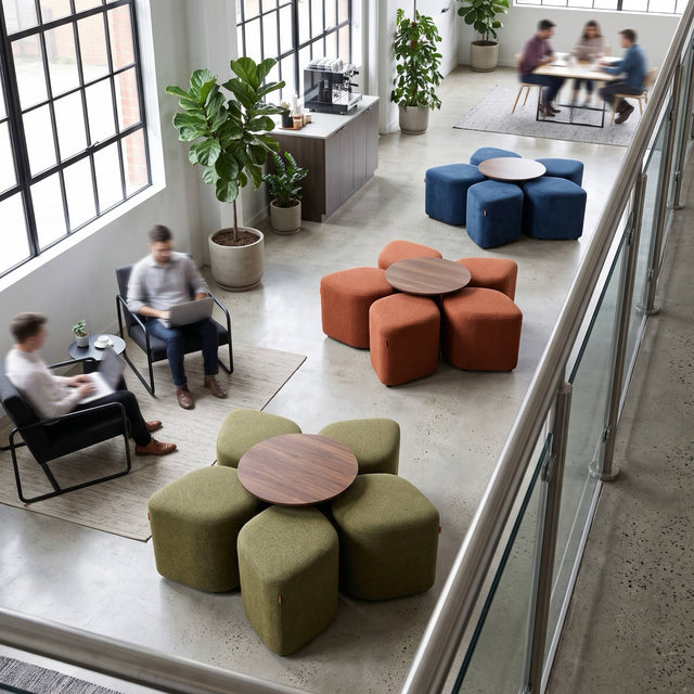Three Blossom seating systems with table furnish a communal area in a modern office. When stored neatly under the table, the arrangement of the poufs create a 5-petal flower shape.