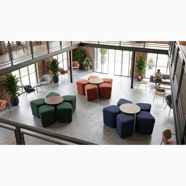 Inside this office, a modern, loft-style lounge features three sets of Blossom seating systems with tables. Each system is neatly organised, with all five poufs docked under their respective tables.