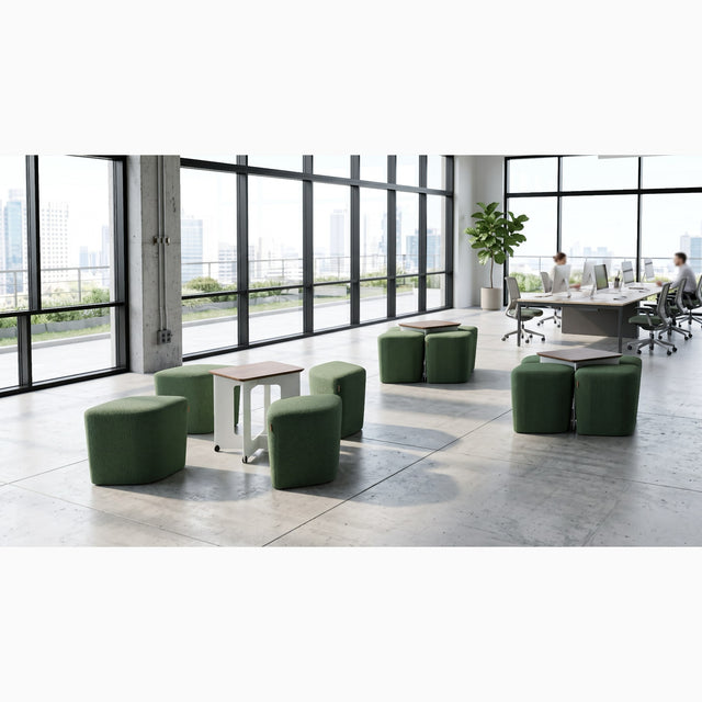 A communal space in an open plan office features three Rhombic seating systems with green poufs and walnut tables. One Rhombic system has its poufs pulled out from under its table ready for use, while the other two systems remain neatly squared away.
