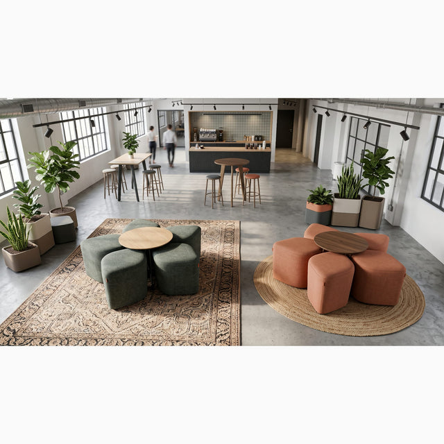 A break area in a modern workplace features 2 Blossom seating systems. One has green poufs with an Oak table and the other has orange poufs with a Walnut table.