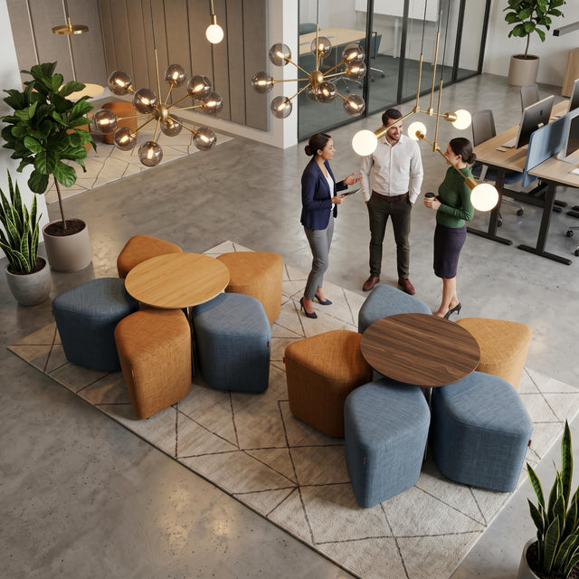 Two vibrant Blossom seating systems bring colour to a trendy, open-plan office breakout space. One setup features yellow poufs and the other blue, with both configurations centred around Walnut tables.