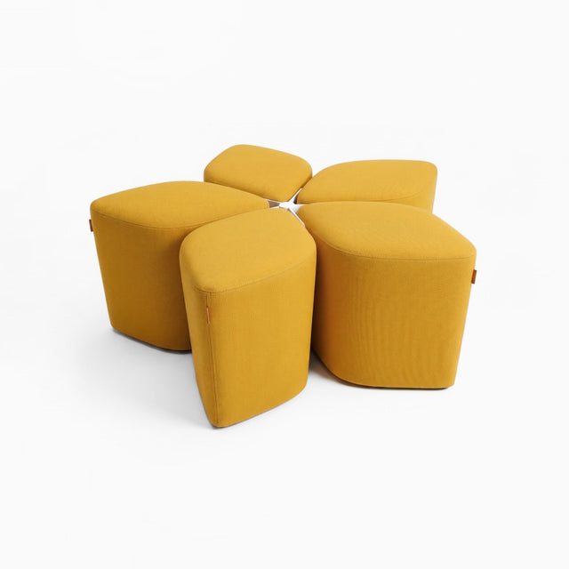Five diamond-shaped poufs in mustard yellow fabric arranged around a docking base, creating a flower-like formation.