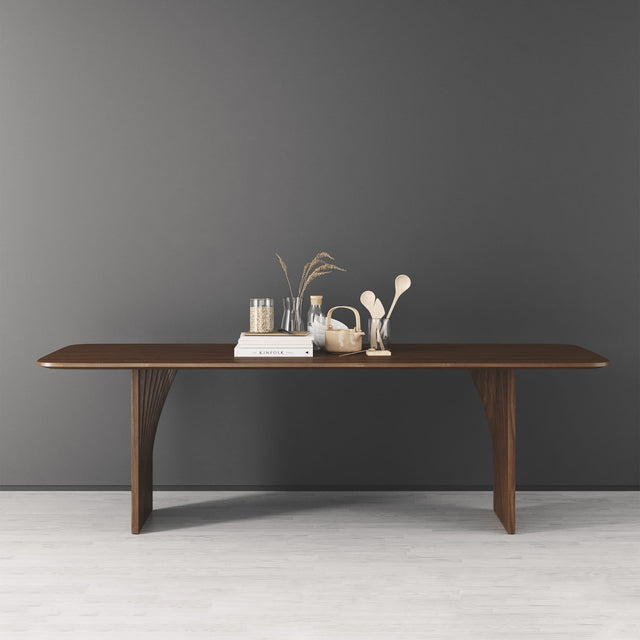 A Sheer dining table in solid Walnut. Its two bases are crafted from layers of lofted, curved wooden slats.