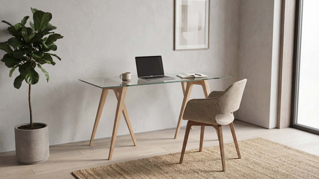 A pair of Flex Desk Trestle Legs, in Ash, with a clear glass tabletop in a contemporary home office.