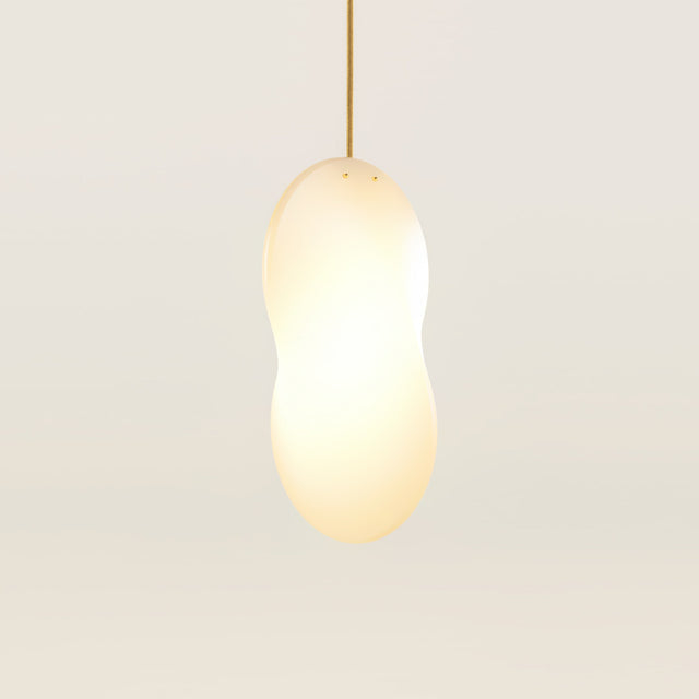 An illuminated Oh Lloyd pendant light with a warm-white light source, gold cable flex and brass studs.