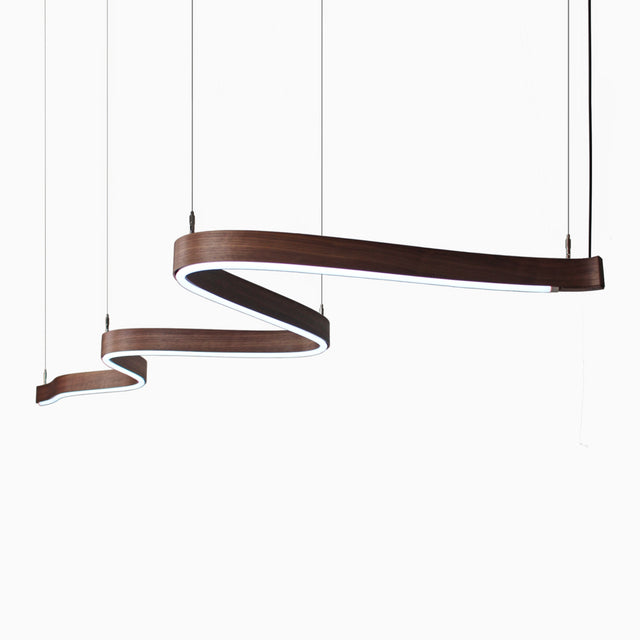 A Scribble suspension luminaire with a walnut body and cool white light source. Its design is inspired by a scribble mark.