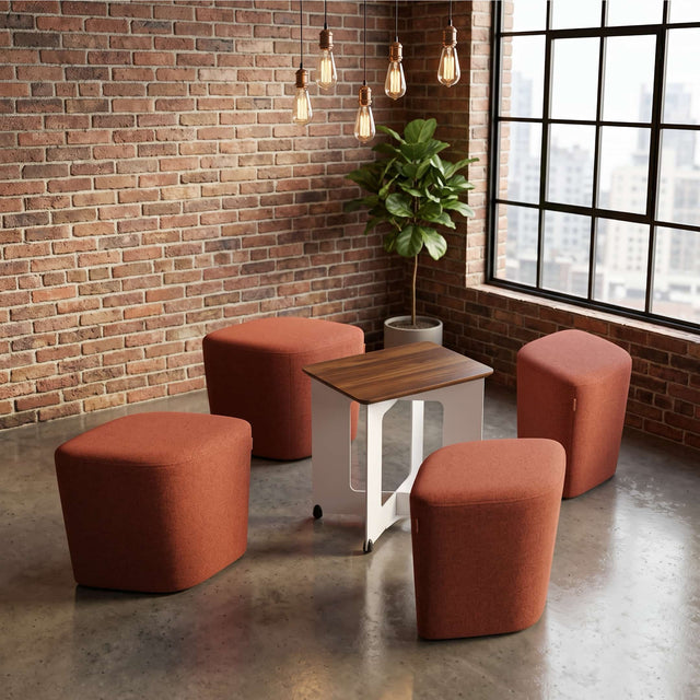 A Rhombic seating system in the breakout area of a modern, trendy office. Its four poufs have been pulled away from their table to be used for a group meeting.