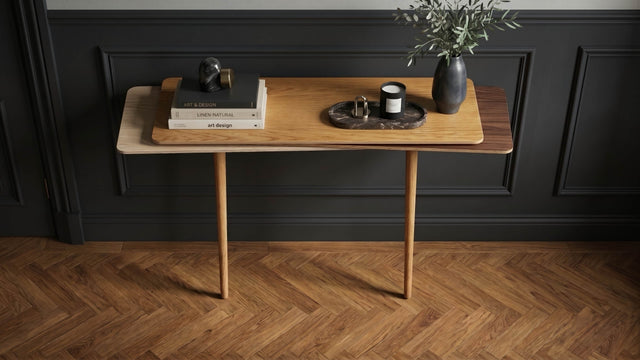 A beautifully decorated hallway with dark wall panels and a herringbone wood floor features a Stacked console table. The console has an Oak top, Walnut middles and Ash bottom with oak legs.