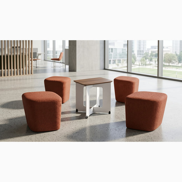 The four red-orange poufs of the Rhombic seating system are scattered around the central table after an impromptu meeting. 