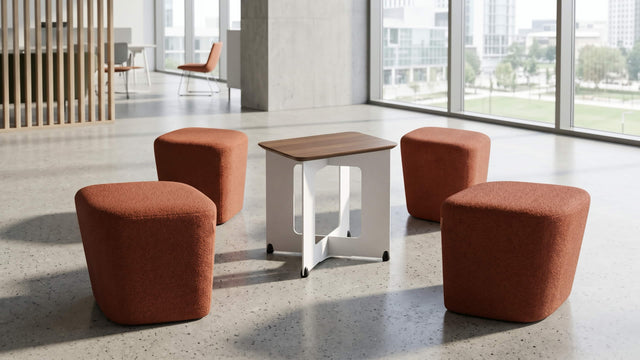 The four red-orange poufs of the Rhombic seating system are scattered around the central table after an impromptu meeting. 