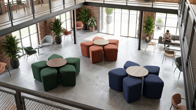 Inside this office, a modern, loft-style lounge features three sets of Blossom seating systems with tables. Each system is neatly organised, with all five poufs docked under their respective tables.