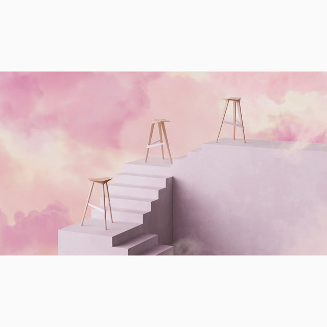 Three solid Oak Delta bar stools perched on a staircase high up in the clouds in an abstract sunset setting.