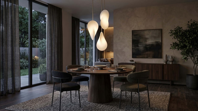 Three Oh Lloyd! pendant lights create a focal point over a round dining table in a modern living space. The lights are staggered at different height and orientated at different angles, showing off Oh Lloyd's unique form, whilst emitting a soft warm glow that illuminates the room.
