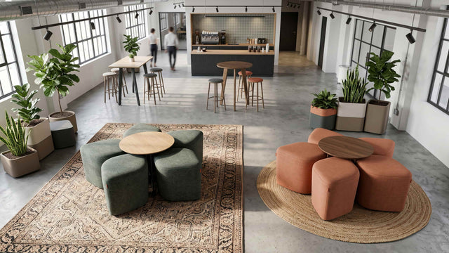 A break area in a modern workplace features 2 Blossom seating systems. One has green poufs with an Oak table and the other has orange poufs with a Walnut table.