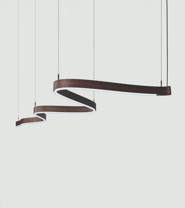 A Scribble suspension light in Walnut with a RGB light source. Users can select either a static or looping colour mode.
